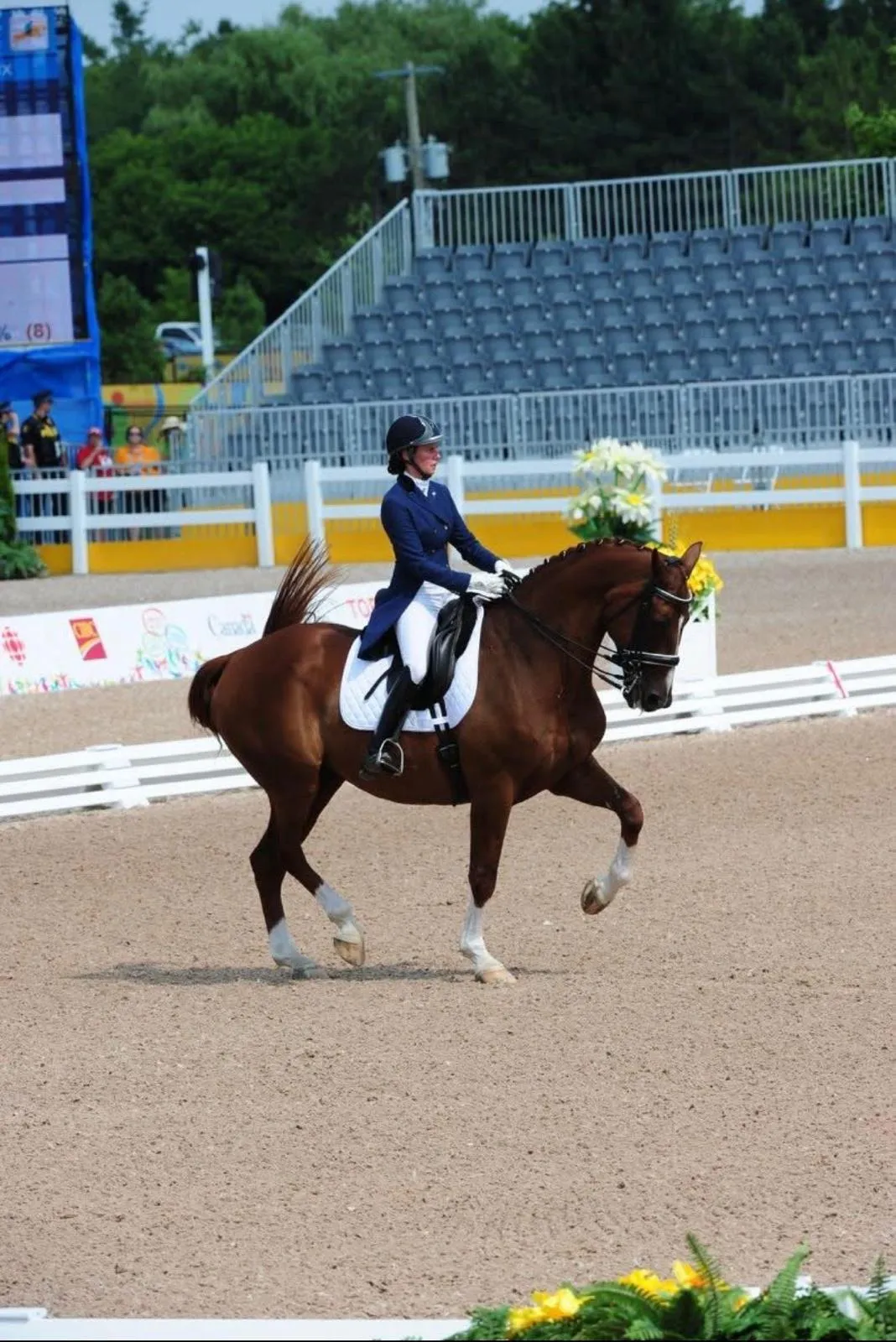 Mica Mabragaña with a chestnut horse in a competition arena with empty grandstands behind